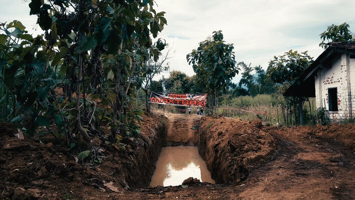 Off-road mud obstacle course prepared for a 4x4 adventure event, featuring a deep water trench surrounded by trees and rugged terrain in a rural outdoor setting.