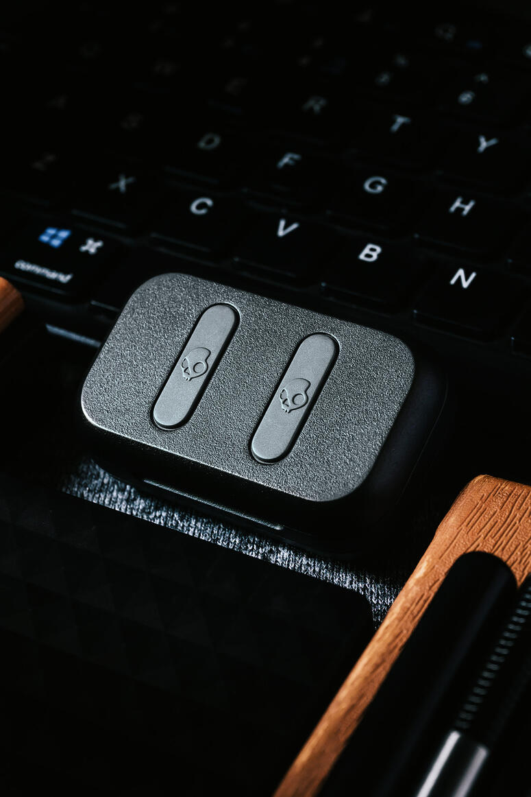 Close-up of a black device with two skull icons on buttons, placed on a laptop keyboard with visible keys.